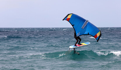 surfer in windfoil sailing through the waves