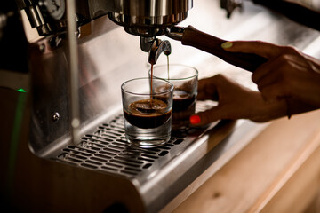freshly brewed hot espresso is poured from the coffee machine into glass cups