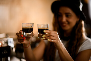 two transparent glass cups with delicious espresso in hands of smiling young woman barista