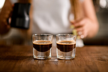 two transparent glasses of freshly brewed espresso on wooden table