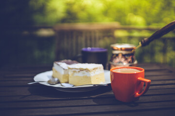 Rustic breakfast. Wooden coffee table with coffee cups, cezve, lake Bled cream cake