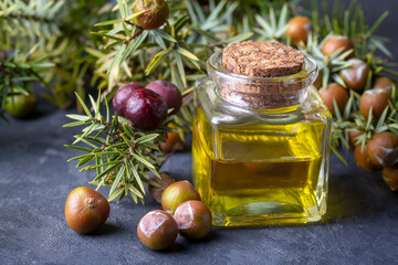 A bottle of essential oil with fresh juniper twigs