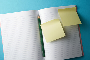 blank note pad with pencil with sticky note on blue background