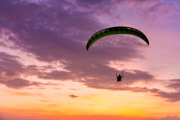 Skydiving sunset landscape of parachutist flying in soft focus. Para-motor flying silhouette with sun set. Silhouette of paraglider flying in the evening sky with sunset.