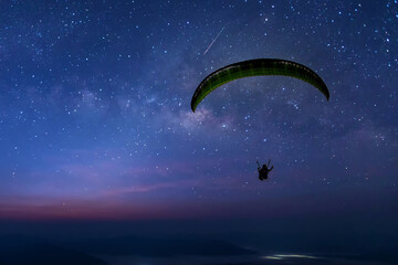 Skydiving night landscape of parachutist flying in soft focus. Para-motor flying silhouette with...