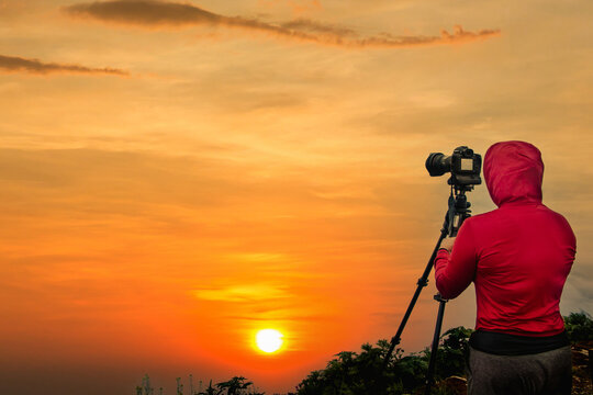 Photographer taking Thailand travel twilight sky photography. Woman photographer shooting with tripod and DSLR camera at sunset  with beautiful landscape twilight sky background.