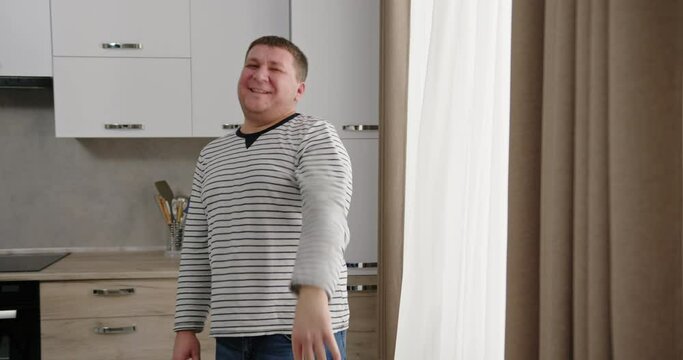Funny man waves hands rejecting from proposition in kitchen