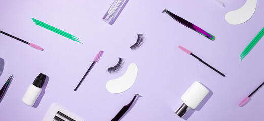 Tools for eyelash extension on a lilac background. Artificial eyelashes, self-care. Tweezers, glue, and other tools for lashmaker work. Top view, copyspace.