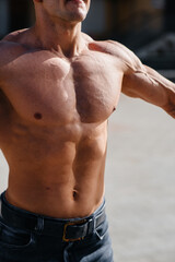 Obraz premium A young sexy athlete with perfect abs trains topless in jeans outside on a sunny day. Healthy lifestyle, proper nutrition, training programs and nutrition for weight loss.