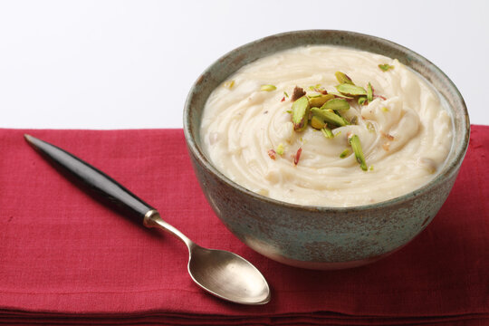 Shrikhand is an Indian sweet dish made of strained curd, garnished with dry fruits and saffron. Served in a ceramic bowl.
