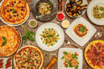 Fototapeta na wymiar Top view image of typical Italian dishes with lots of basil, pizzas, pasta, gnocchi, tomatoes and vegetables