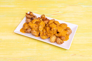 Portion of spicy patatas bravas to share in a typical Spanish tapas restaurant