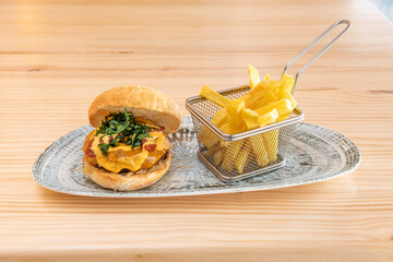 Spectacular beef burger with a lot of cheese, fried arugula and Italian dehydrated tomato with a portion of French fries as garnish
