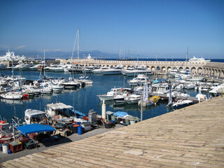 Scenic panoramic seaside view with old castle Antibes and many large yachts on a sunny day. People enjoying life in the summer sail on a yacht. Wonderful travel vacation with swimming in Azure Coast.