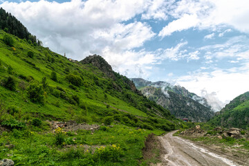Fototapeta na wymiar Mountain road and storm clouds over alpine meadows 