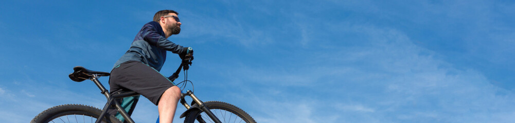 Conquering mountain peaks by cyclist in shorts and jersey on a modern carbon hardtail bike with an...