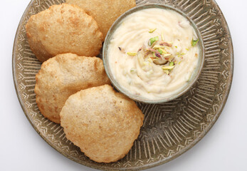 Shrikhand & Puri, Shrikhand is an Indian sweet dish made of strained curd, garnished with dry fruits and saffron. Served with Puri, Deep fried flat bread.
