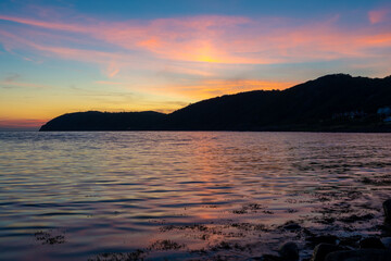 Gorgeous summer sunset with Kullaberg peninsula in silhouette. Long exposure photo taken from Molle harbor in Sweden.