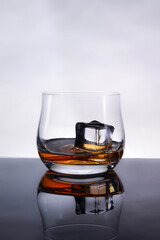 glasses of whiskey with ice cubes on black glass surface