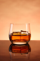 glasses of whiskey with ice cubes on black glass surface
