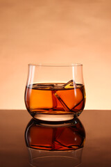 glasses of whiskey with ice cubes on black glass surface