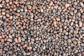 Natural expanded clay is a light and porous building material. The texture and pattern of the stone in granules. Brown background.