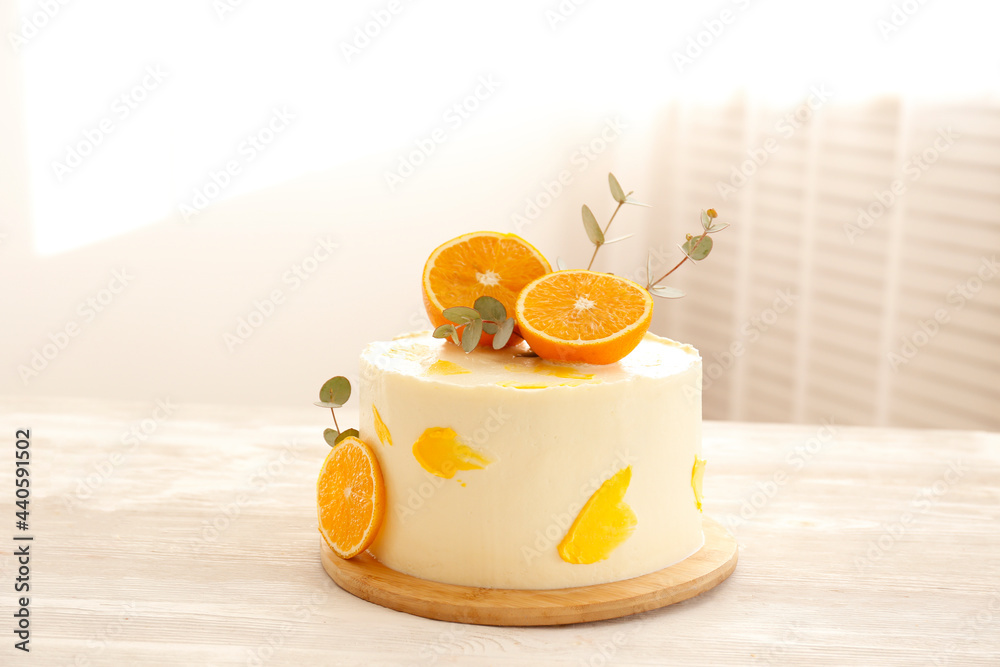 Wall mural Minimalistic single tier wedding cake with white icing and sliced orange and eucalyptus decoration. Close up, copy space for text, background, top view.