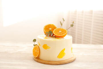 Minimalistic single tier wedding cake with white icing and sliced orange and eucalyptus decoration. Close up, copy space for text, background, top view.