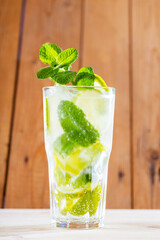 Mojito cocktail on wooden boards. Summer cocktail in the rustic style. Refreshing drink with lime, mint and ice. Trendy beverage