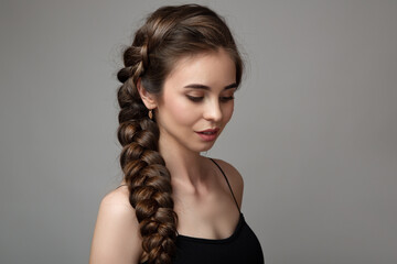 Portrait of a cute woman on a gray background with a braid hairstyle. long bushy tail