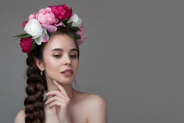 Naklejka premium portrait of a young woman with a rim of peonies on her head. Beauty and flower care