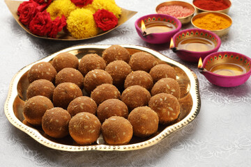 Rava Laddu or Semolina Laddoo Or Rawa Ladu, a popular sweet dish from Maharashtra, India, arranged in a plate with flowers aside