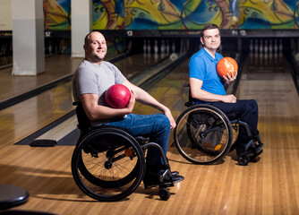 Two young disabled men in wheelchairs playing bowling in the club