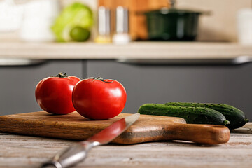 Close-up ripe tomatoes on a cutting board. Kitchen accessories. Chopping wooden boards and utensils. Fresh and tasty vegetables. Farmed organic products. Modern kitchen still life. Selective focus