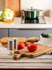 Vertical shot fresh vegetables on a cutting board. Kitchen accessories. Chopping wooden boards and utensils. Ripe tomatoes and cucumbers. Farmed organic products. Modern kitchen still life.