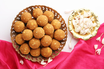 Rava Laddu or Semolina Laddoo Or Rawa Ladu, a popular sweet dish from Maharashtra, India, arranged in a plate with flowers aside