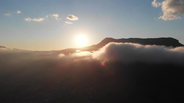 The sunset in mountains through the clowds