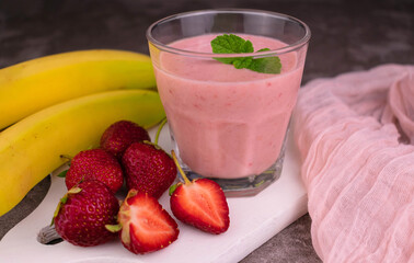 A glass of strawberry banana smoothie on a gray background.