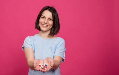 Beautiful young woman holding many pills in her hands