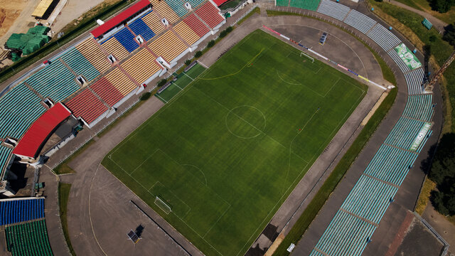 Football stadium in the city park. A green field and stands are visible, painted in different colors. Close-up shot. Aerial photography.