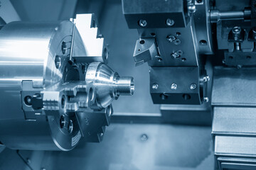 Obraz na płótnie Canvas The CNC lathe machine thread cutting the metal cone shape parts. The hi-technology metal working processing by CNC turning machine .