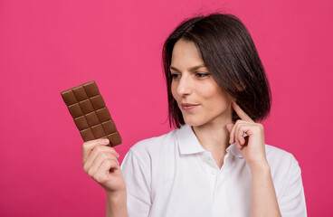 Beautiful young woman holding a bar of chocolate in her hand
