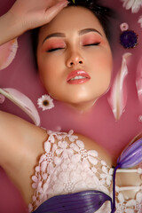 Beautiful portrait of a woman with flowers and petals in rose water. Facial cosmetics that moisturize the skin