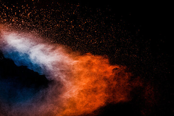 Orange blue  powder explosion on black background.Orange blue color dust splash clouds.