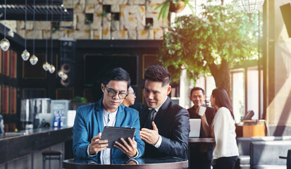 Group of Asian businessman wearing suits talking using digital tablet together while standing in conference room. Two asian businessman discussing ideas concept. business, people