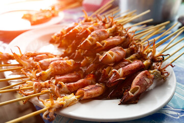 Fresh grilled squid on charcoal grill,Roast octopus on white plate.Seafood on street food,Thailand.