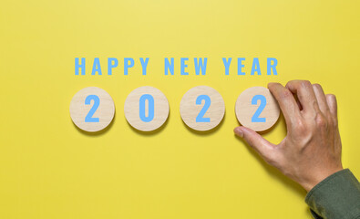 Happy new year 2022. Wooden cube with the number 2022 with HAPPY NEW YEARword on yellow background. Start concept