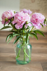 Naklejka na ściany i meble Bouquet of fresh pink peonies in transparent jar standing on the table indoors