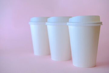 Three white paper coffee cups on pink background, coffee cup mock up.