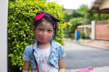 Little asian girl wearing mask for protect corona virus outbreak.Home school.